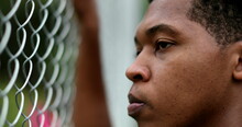 Pensive Angry Young Black Man Leaning On Metal Fence Outside Thinking