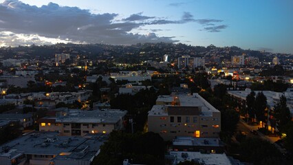 Aerial view of illuminated cityscape on cloudy sunset sky background