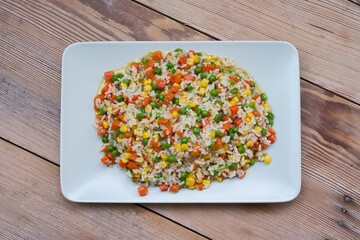 Poster - Risotto, with corn, carrot and peas on a wooden table.