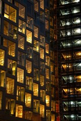 Wall Mural - Vertical shot of an office building windows illuminated at night