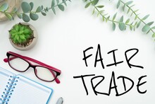 Vector Of Conceptual Caption 'Fair Trade' With Notebook And Glasses Adorned With Plants
