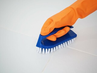 Wall Mural - Woman wearing orange gloves hand brushing toilet bathroom floor. closeup photo, blurred.