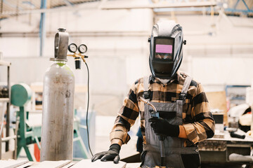 Wall Mural - A factory worker with mask preparing for welding metal parts.