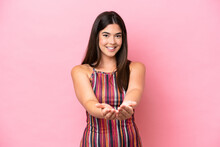 Young Brazilian Woman Isolated On Pink Background Holding Copyspace Imaginary On The Palm To Insert An Ad