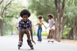 © amorn - Happy young boy playing on roller blades in the park, African American young boy riding roller blades in the garden, Kid practicing roller blades.
