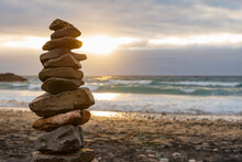 Close Up Of A Stack Of Stones Balance On A Beach Against A Cloudy Sky At Sunset Time.Zen Concept