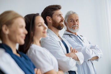 Wall Mural - Group of professional doctors standing in a line keeping arms crossed at the modern clinic