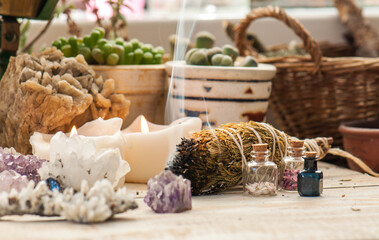 Cozy space with candles, crystals, herbs, and plants. Alternative medicine, herbal medicine, aromatherapy or esoteric background with incense smoke.