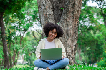 A happy African American woman works in the garden. Cheerful African American woman relaxing in the park during the summer.