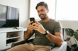 © kleberpicui - Young man using cellphone in the living room