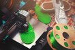 custom FDM-printer makes a shoe sole with distinct inner structure from bright green plastic filament. comfy bright home scene with persian rug, grey sneaker shoes and filament spools. selective focus
