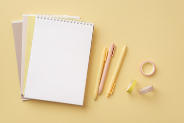 School supplies concept. Top view photo of stationery copybooks adhesive tape and pens on isolated pastel yellow background with empty space