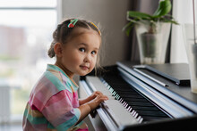 Cute Little Girl Playing Piano At A Music School.