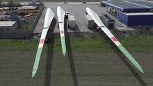 Three Trucks Loaded With Wind Turbine Blades Are Parked In The Parking Lot Of A Gas Station