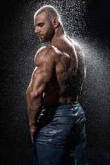 Wall Mural - Muscular man under the rain in studio. Sexy male in water drops