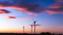 Silhouette Of Three Modern Windmills Under A Blueish Sunset On The Outskirts Of Kiyú, San José, Uruguay