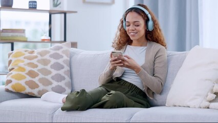 Poster - Woman streaming music on her phone while wearing wireless headphones and relaxing at home. Cheerful female sitting on cozy couch enjoying and grooving to favourite songs on an app over the weekend