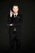 © Arunporn - Portrait of handsome businessman in black suit showing okay symbol hand isolated on black background