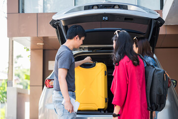 Rear of Asian friends put luggage to SUV car to start vacation trip