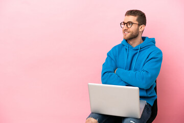 Poster - Young man sitting on a chair with laptop with arms crossed and happy