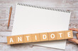 解毒剤のイメージ｜「ANTIDOTE」と書かれたブロック、ノート、ペン、手

