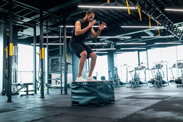 Wall Mural - Motivated black male athlete doing balance exercise on cube in modern gym