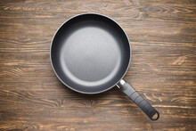 New Frying Pan On A Wooden Background. Top View.