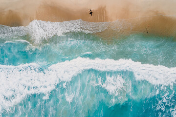 Wall Mural - Surfer on tropical sandy beach with blue transparent ocean and waves. Aerial view