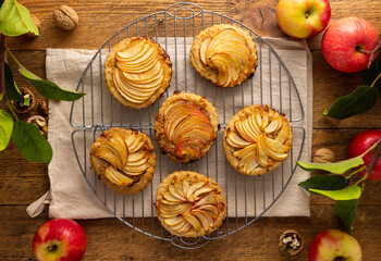 Mini Apple pie tartlets with walnut on wooden table. Delicious dessert for autumn winter dinner.Top view.