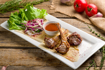 Poster - Rack of lamb with tomato sauce with red onion on old wooden table