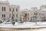 Fototapeta Paryż - Beautiful winter cityscape: buildings, trees and street lamps covered with snow. Inscription on shop in Ukrainian - School child