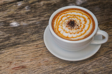 Wall Mural - Closeup Hot Caramelmachiato Cow Milk Thai Blended on white ceramic cup on white ceramic plate,  on wooden floor background, drink, food, copy space