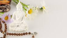 Healing And Meditation, Energetic Health And Relax. Buddha Statue, Prayer Beads, Aroma Sticks And Wild Flowers On A White Background With Copy Space. Vesak, Buddha Day. Soft Image Style
