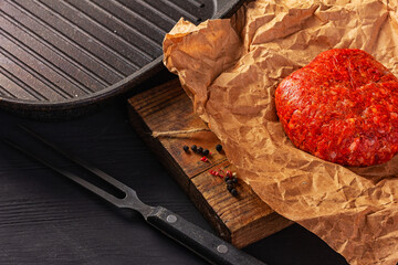 Wall Mural - raw hamburger on cutting board on black wooden background.