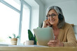 © gstockstudio - Cheerful senior woman using digital tablet while working from home