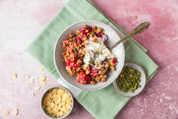 Wall Mural - Strawberry crumble with ice cream and almonds in a plate with spoon on green napkin over pink background