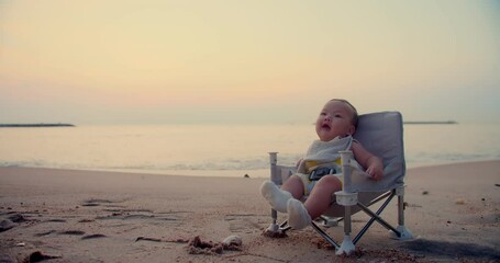 Wall Mural - happy person cute adorable little baby infant smiling carefree relax on outdoor chair at nature ocean sea beach during beautiful sunrise sunset sky in summer holiday enjoy leisure vacation travel