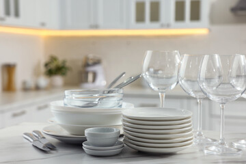 Poster - Different clean dishware, cutlery and glasses on white marble table in kitchen