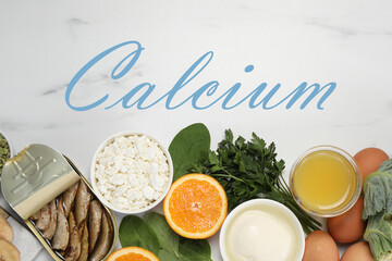 Different fresh products with high amounts of easily absorbable calcium on white marble table, flat lay