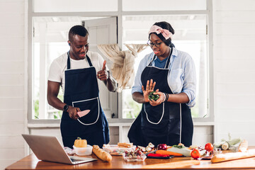 Portrait of love african american couple having fun cooking food together with fresh vegetable salad and sandwich ingredients to prepare the yummy eating in kitchen at home