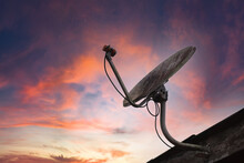 The Satellite Receiver Is Mounted On A Roof With A Golden And Orange Sky Background.