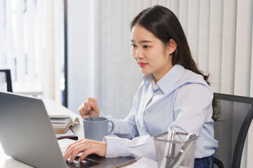 Business concept, Businesswoman drinking coffee and checking of marketing data on laptop in office