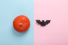 Minimal Halloween Still Life. Pumpkin And Bat On Blue-pink Pastel Background. Top View
