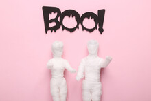 Mummy Doll Wrapped In Bandages With The Slogan Boo! On Pink Pastel Background
