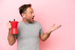 Middle age caucasian man holding coffee pot isolated on pink background with surprise facial expression