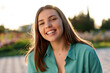 © fotofabrika - Portrait of young woman in green shirt smiling in a park