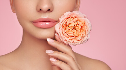 Wall Mural - Beautiful model with a rose. Perfect woman face makeup close up. Lipstick. Beautiful nails. Nice smile. Perfect skin