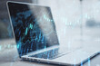 canvas print picture Close up of laptop on desktop with creative glowing forex chart hologram and map on blurry background. Stock, market and invest concept. Double exposure.