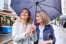 Mother And Daughter With Umbrella Walking Together On Street