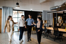Business Colleagues Discussing And Walking Together In Modern Office